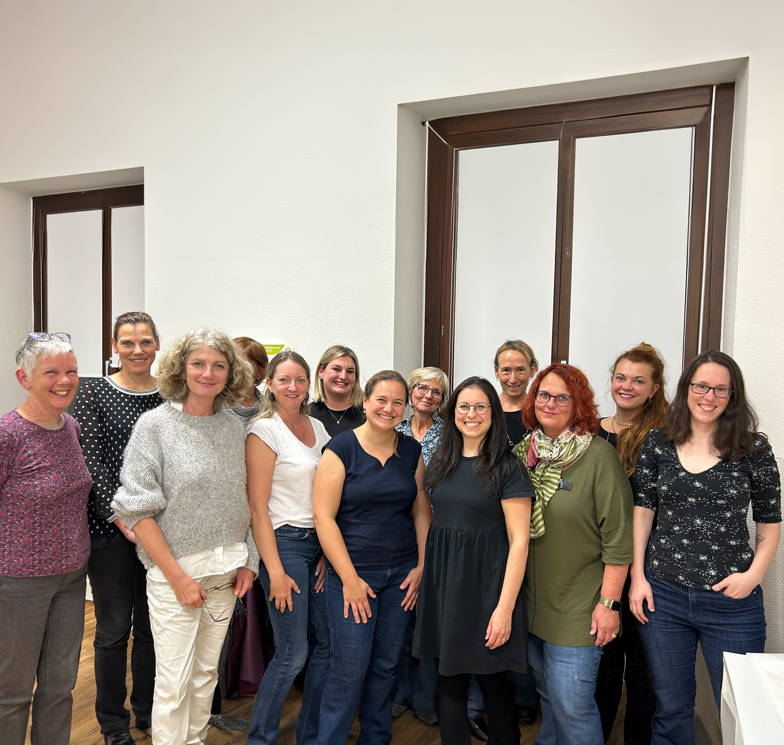 gruppenfoto von sieben lächelnden hebammen in einem innenraum